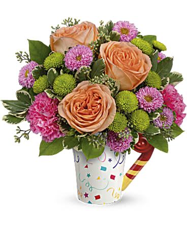 Peach roses and pink flowers in a decorated cup with a candy cane