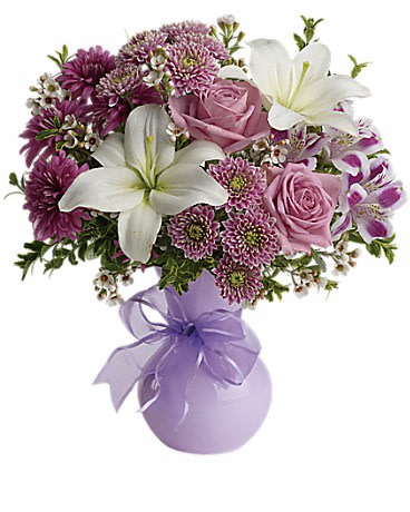 Pink roses and white lilies in a lavender vase with a ribbon