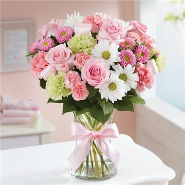 Pink and white bouquet in a clear glass vase with a pink ribbon