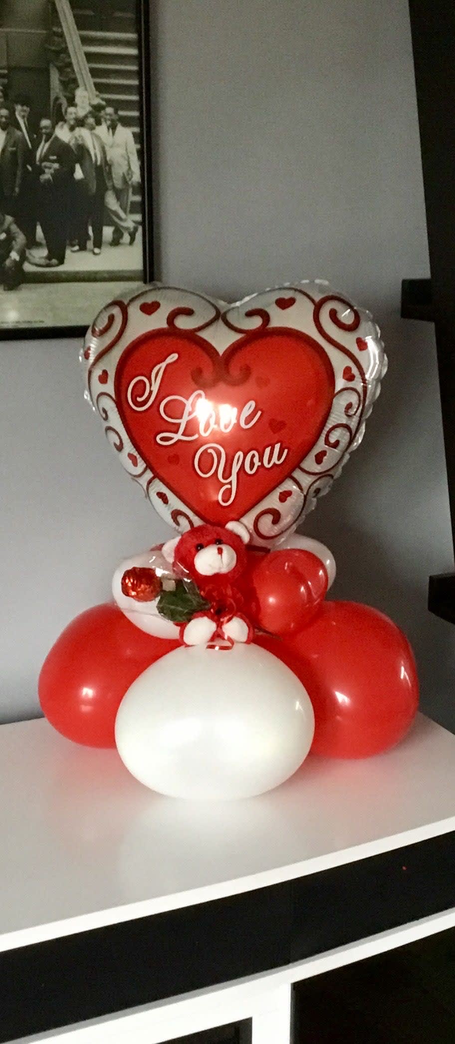 Heart-shaped "I Love You" balloon with red and white balloons and a teddy bear