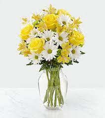 Yellow roses and white daisies in a clear glass vase