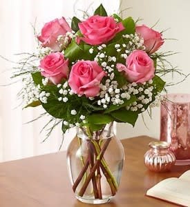 Pink roses arranged in a clear glass vase with baby's breath