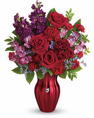 Red roses and purple flowers arranged in a red vase