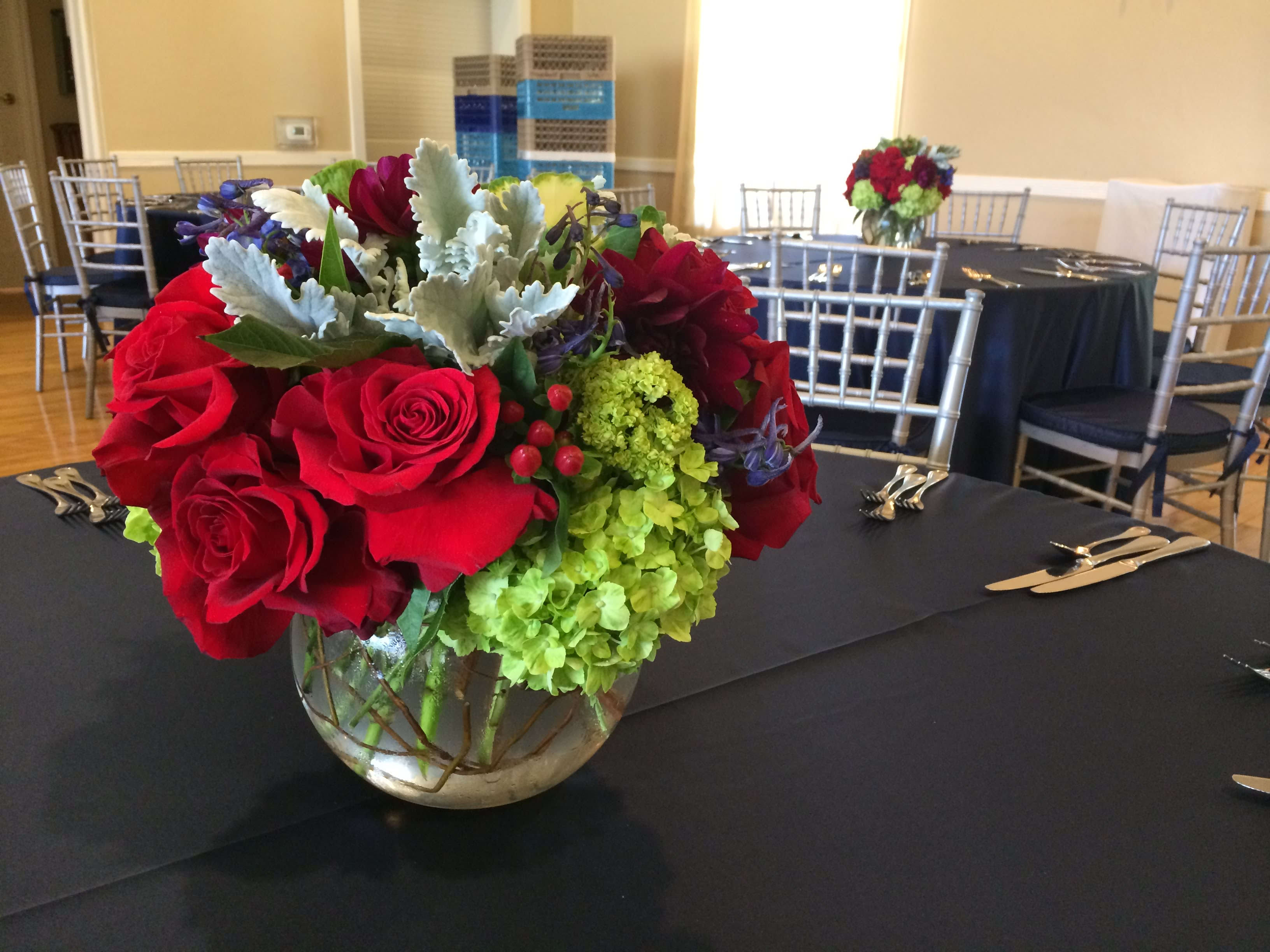Red roses and green hydrangeas in a glass bowl vase on a table