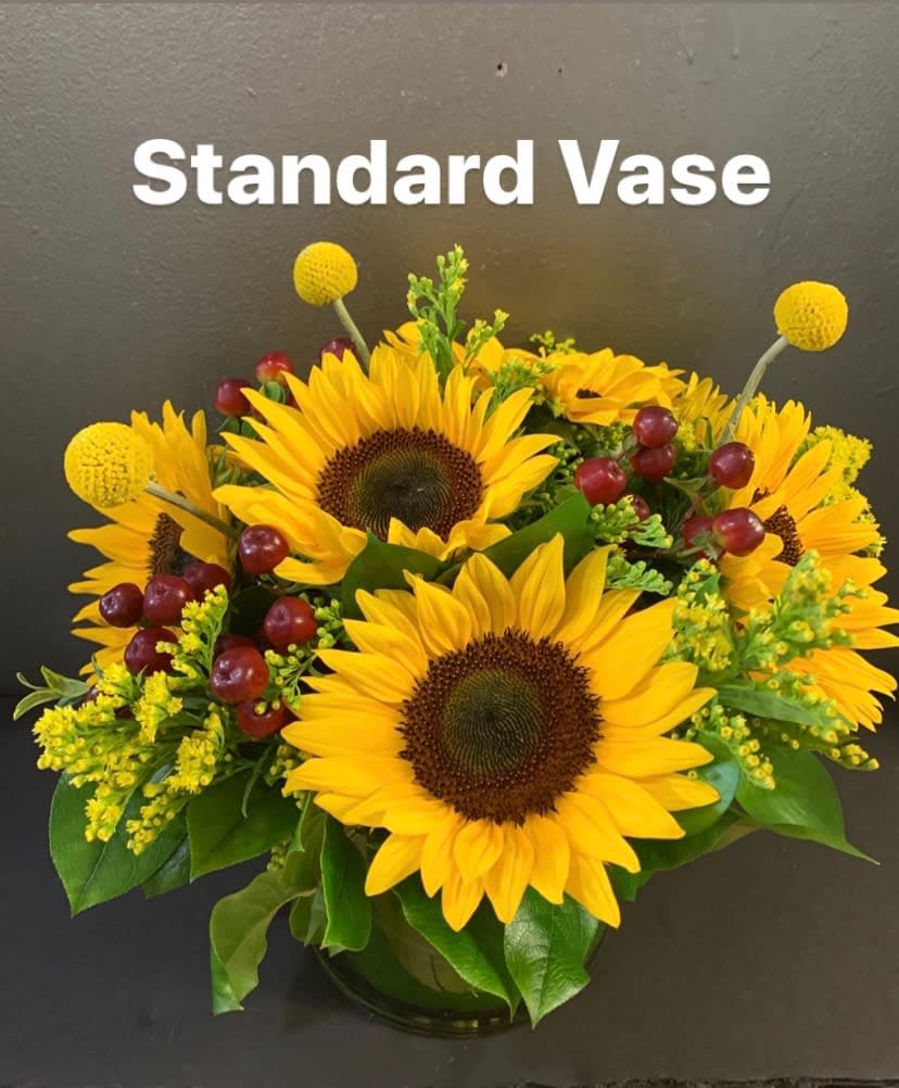 Sunflower arrangement in a vase with yellow accents and red berries