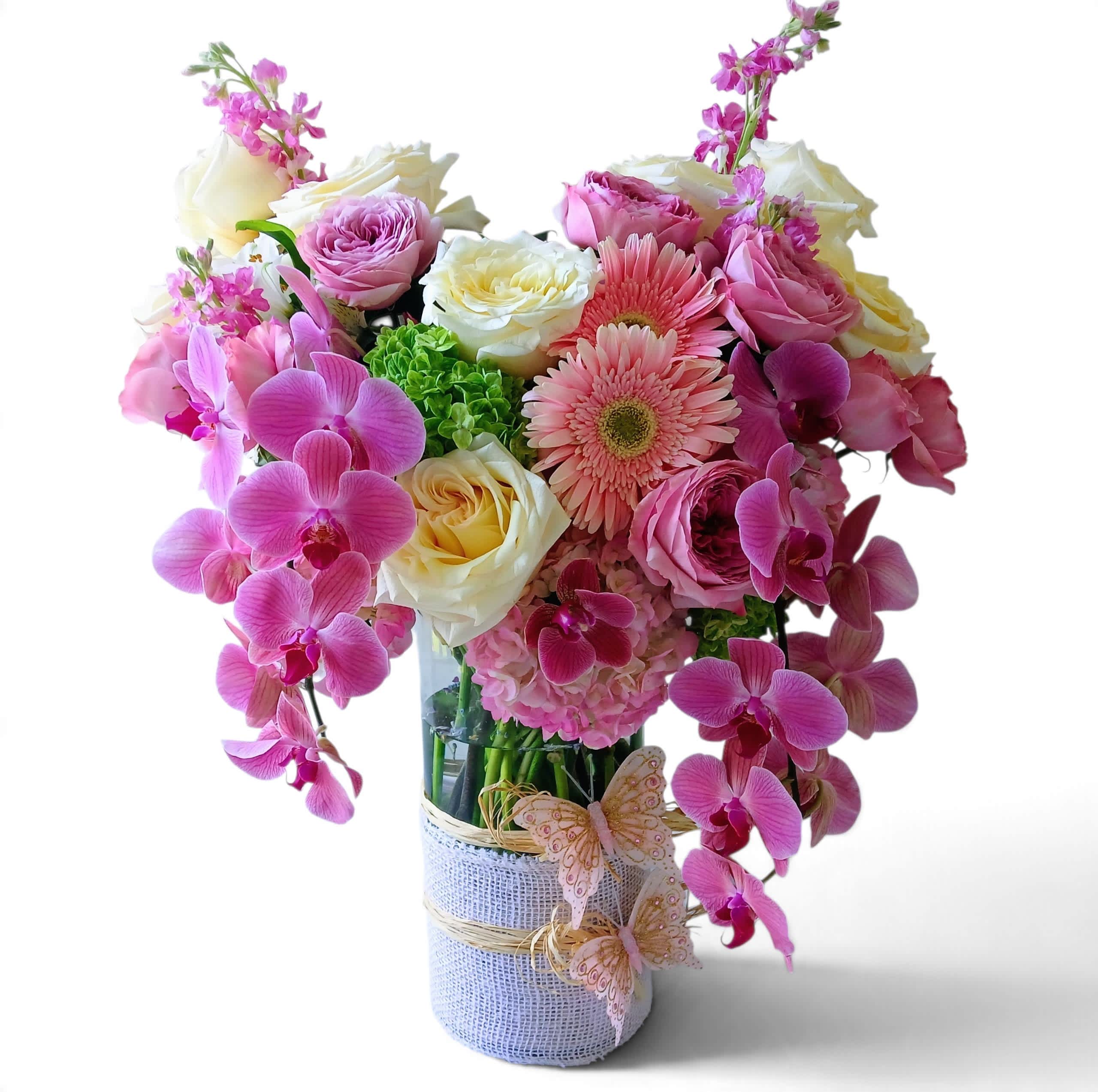 Pink and white floral arrangement in a wrapped glass vase with orchids and roses.