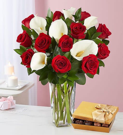 Bouquet of red roses and white calla lilies in a glass vase