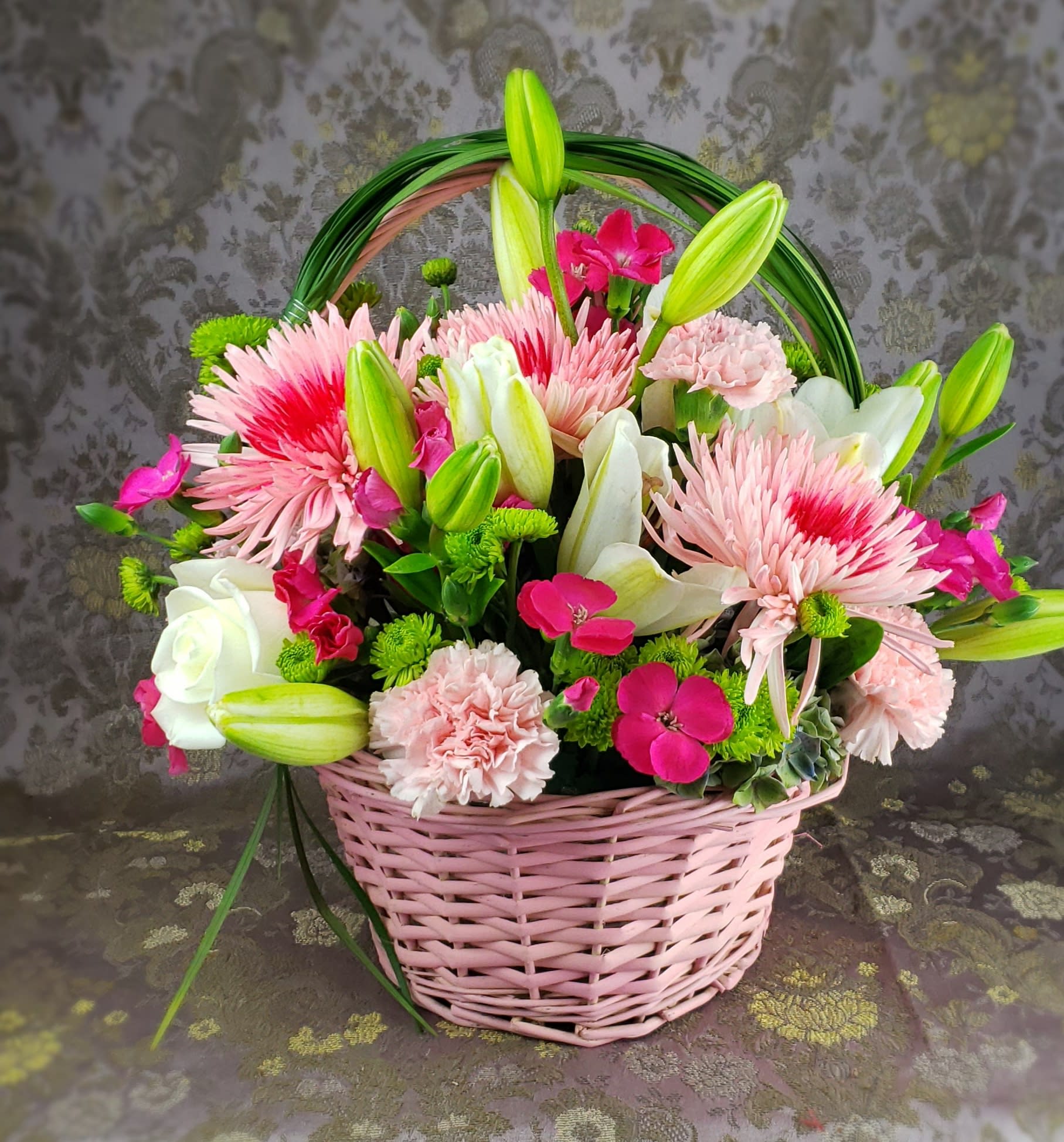 Pink basket of mixed flowers with lilies, roses, and carnations