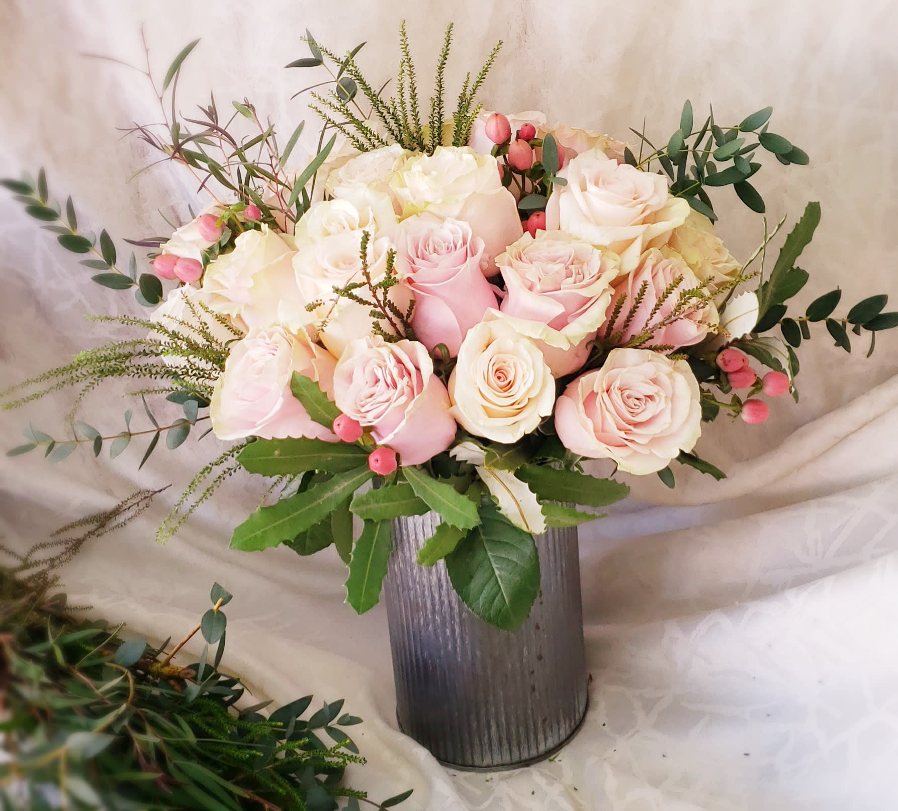 Pink and white roses arranged in a tall metal vase