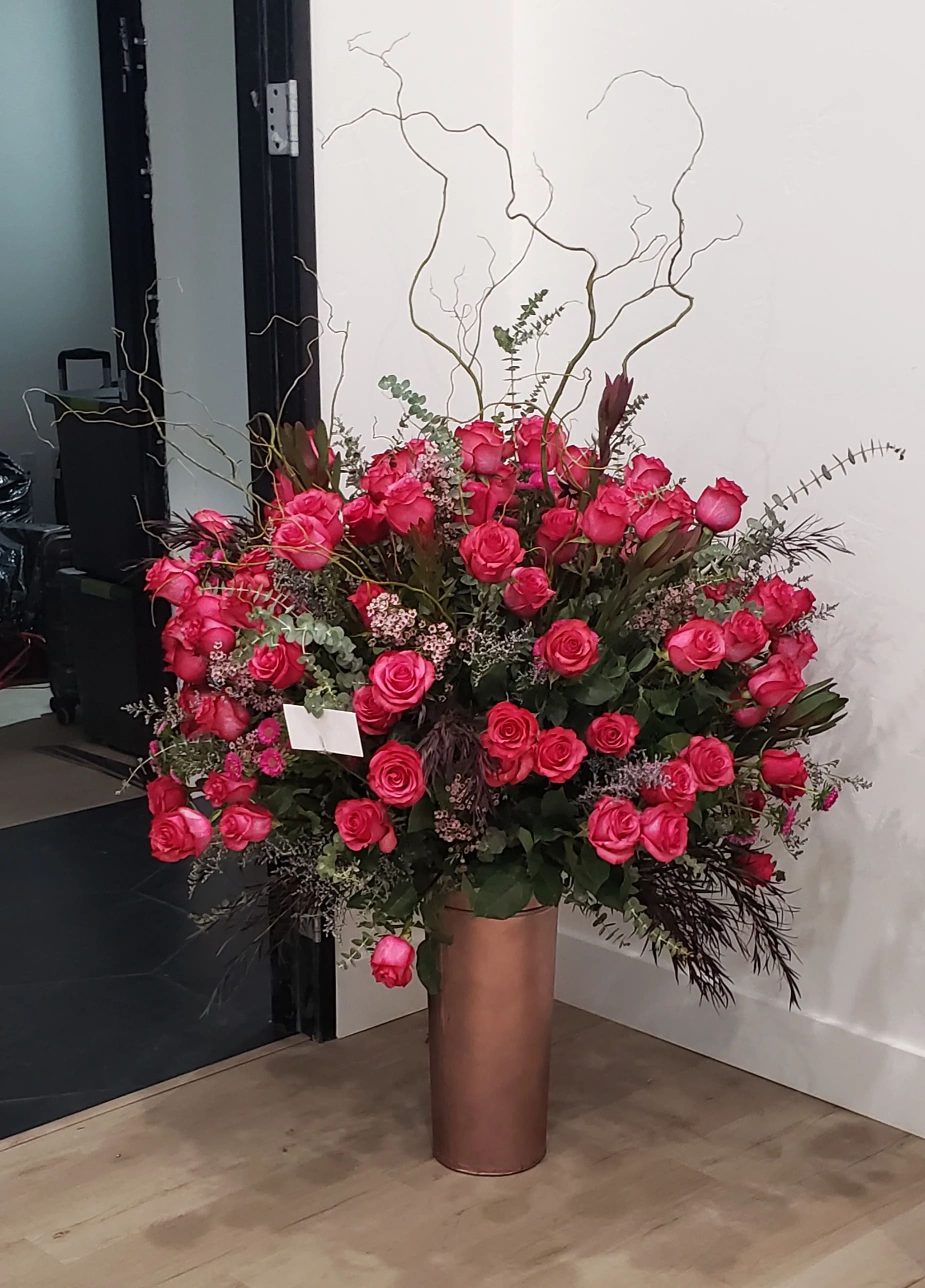 Large arrangement of pink roses in a tall copper vase