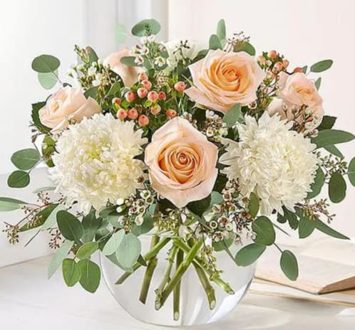 Peach roses and white chrysanthemums in a clear glass vase