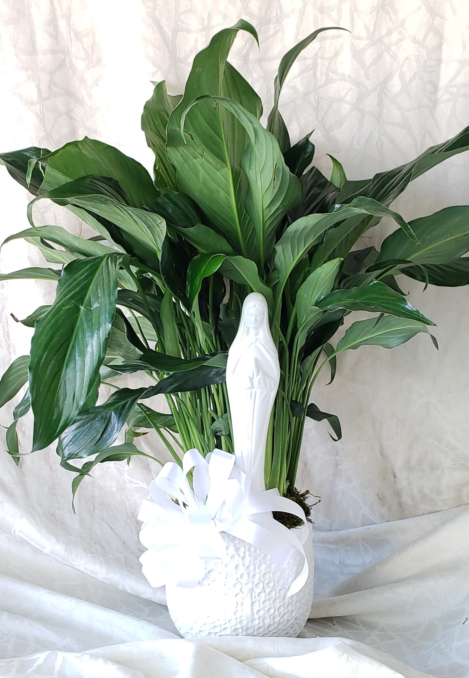Potted green plant with a white figurine and ribbon bow