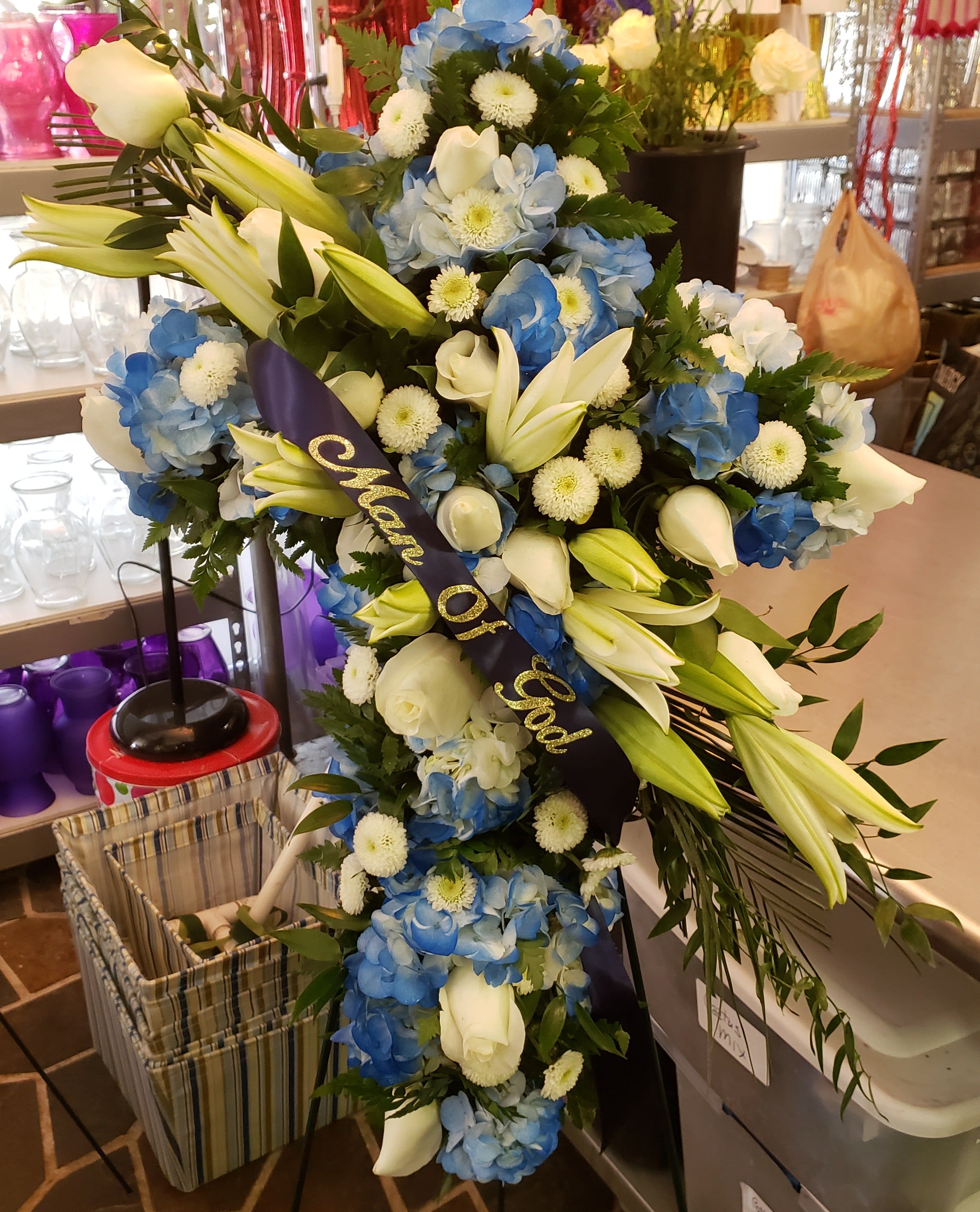 Large blue and white funeral spray with lilies and roses on a stand