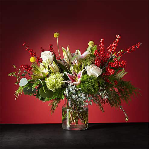 Mixed floral arrangement in a clear glass vase with red berry branches