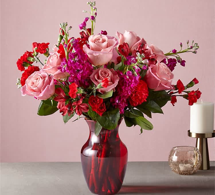 Pink roses and red carnations in a red glass vase