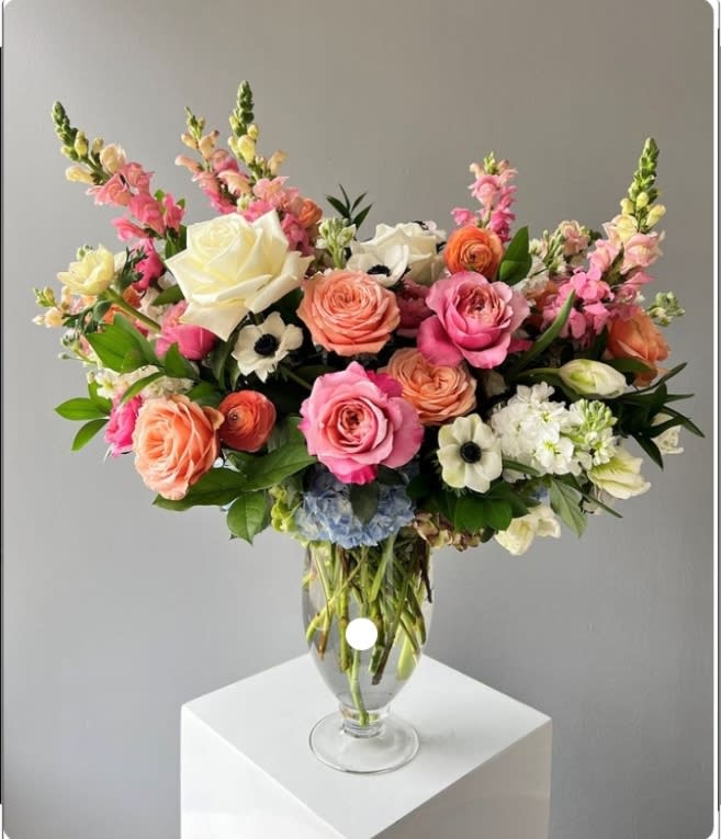 Mixed pink and peach flowers arranged in a clear glass vase
