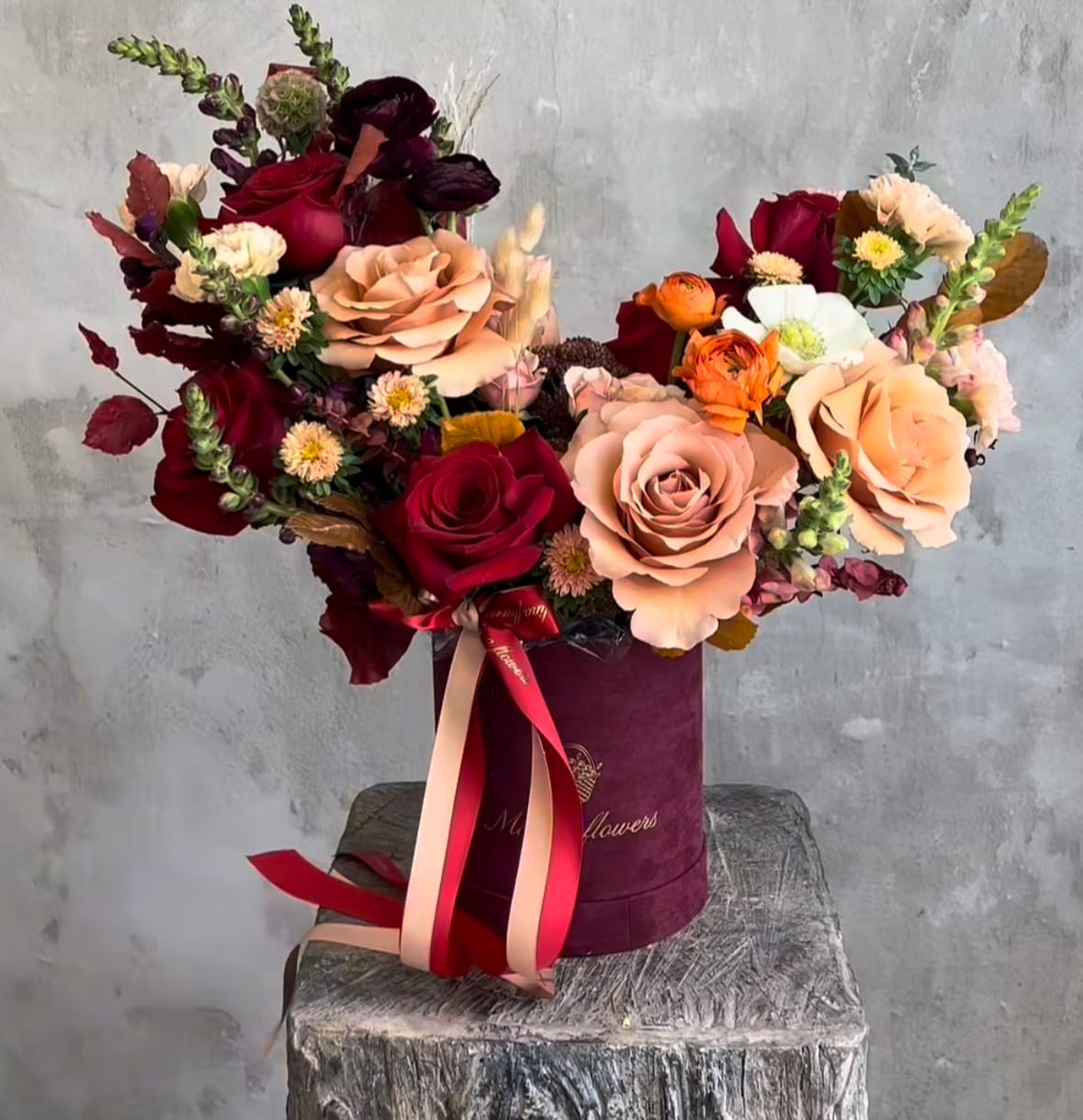 Bouquet of red and blush roses in a burgundy hat box with ribbon
