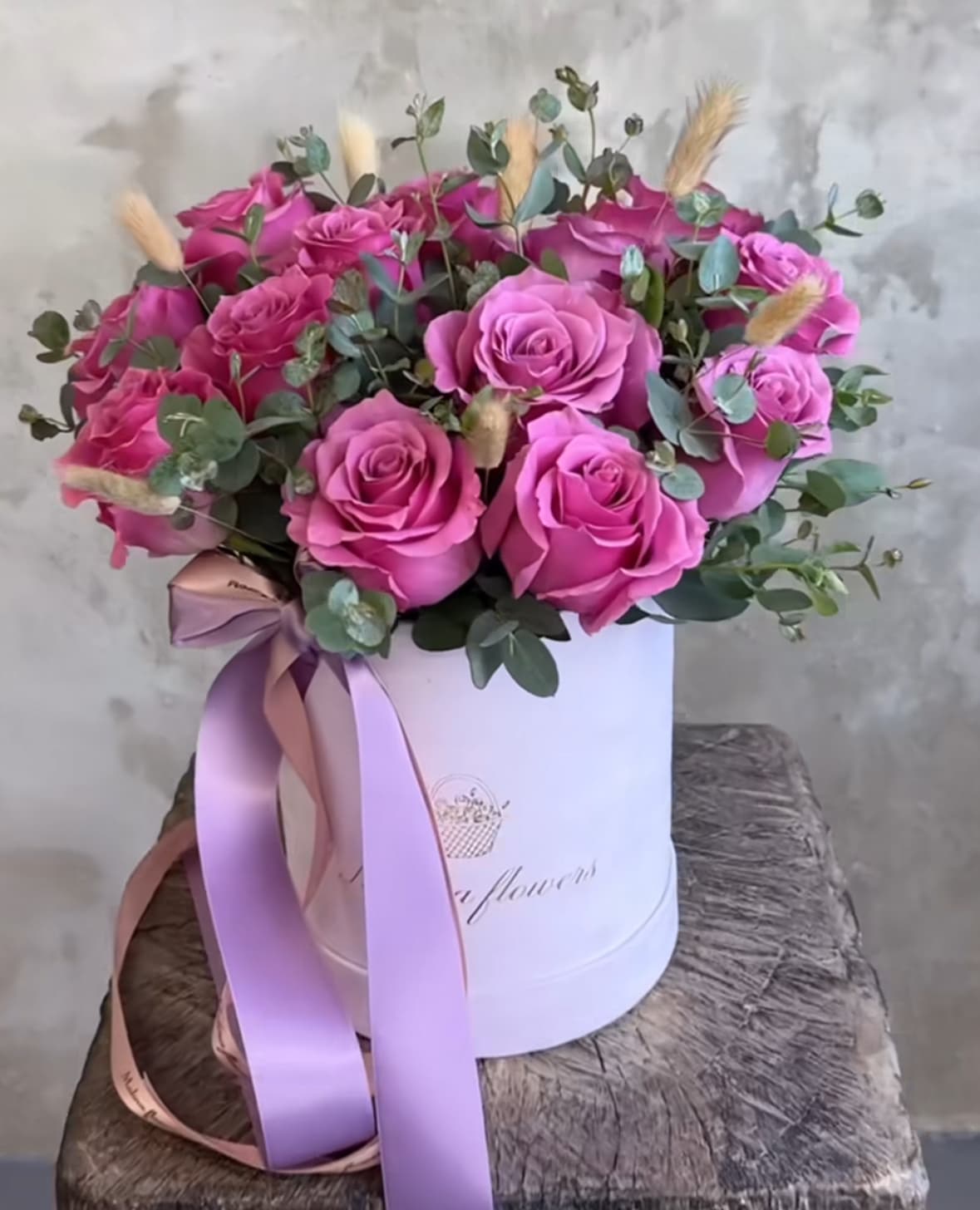 Pink roses arranged in a white hat box with a ribbon