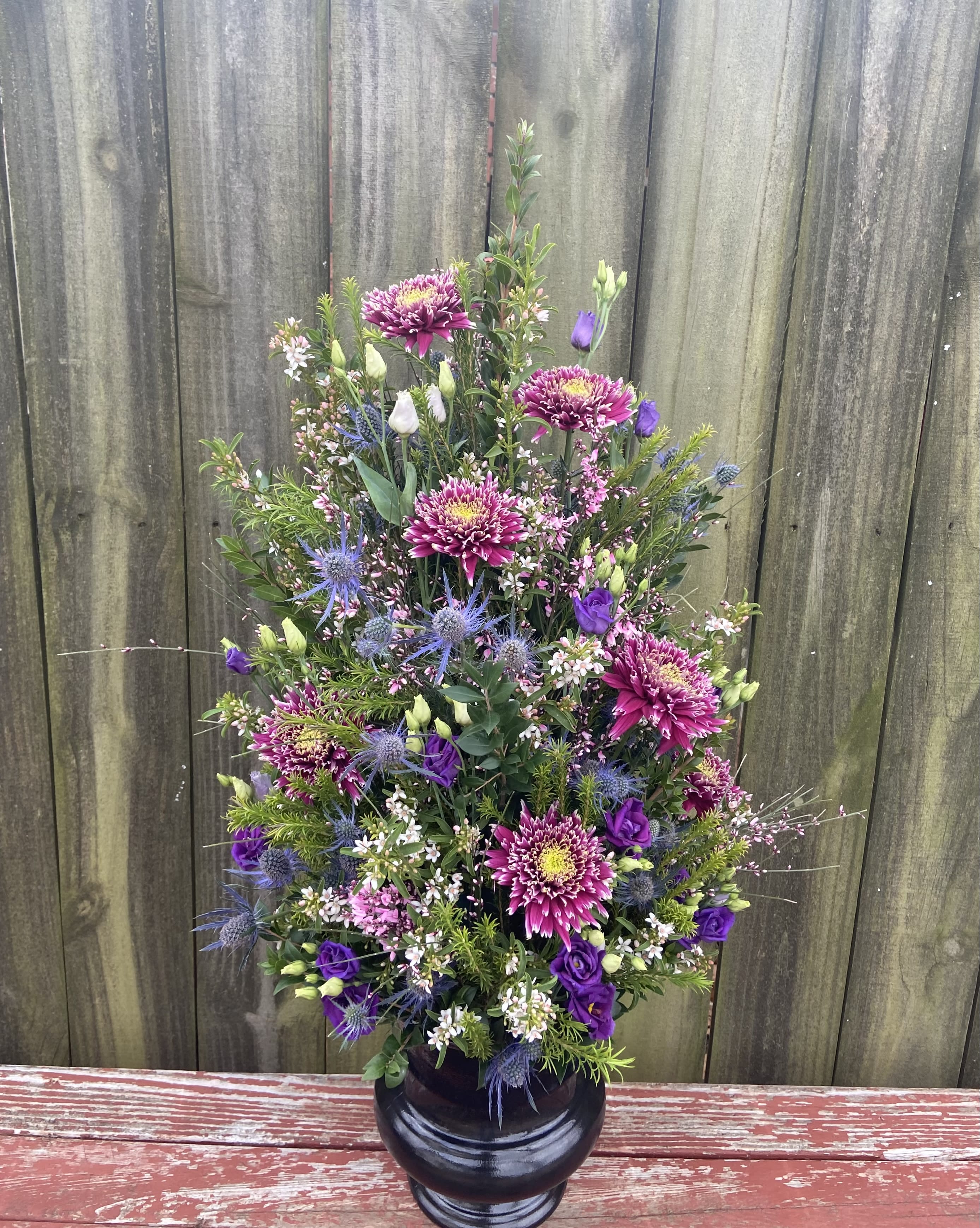 Tall bouquet of purple and pink flowers in a black vase