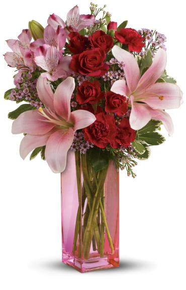 Pink lilies and red roses arranged in a tall pink vase