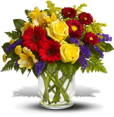 Bouquet of yellow roses, red gerberas, and purple filler in a glass vase