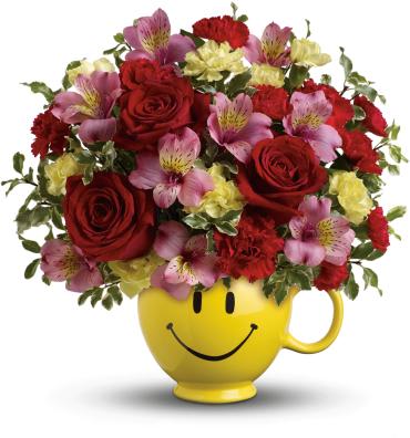 Bouquet of red roses and pink flowers in a yellow smiley-face mug