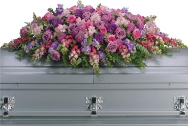 Large pink and purple floral casket spray on a gray casket