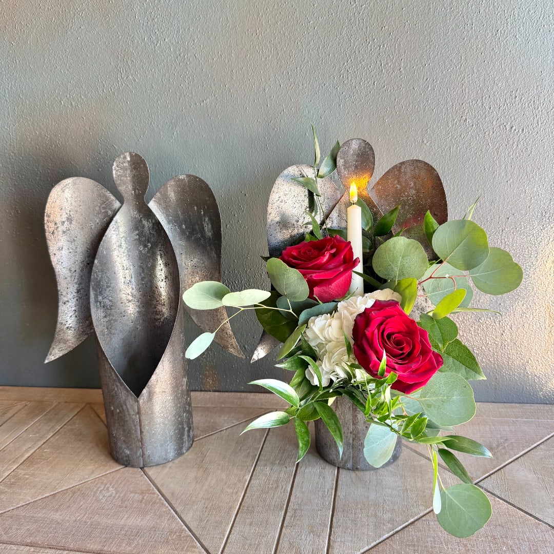 Red roses and white flowers arranged with a candle in a metal angel holder