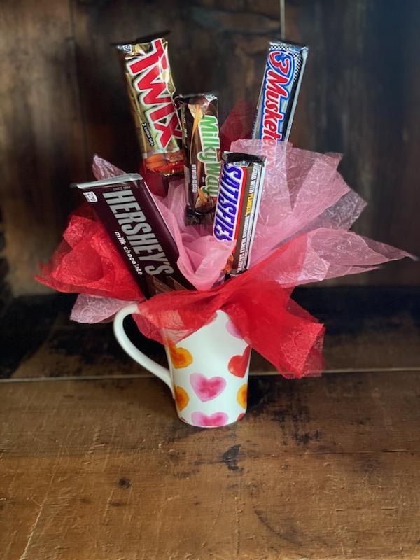 Candy bars arranged in a heart-pattern mug with pink and red tissue paper