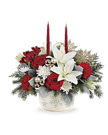 Holiday floral arrangement with red roses, white lilies, and candles in a snowflake vase