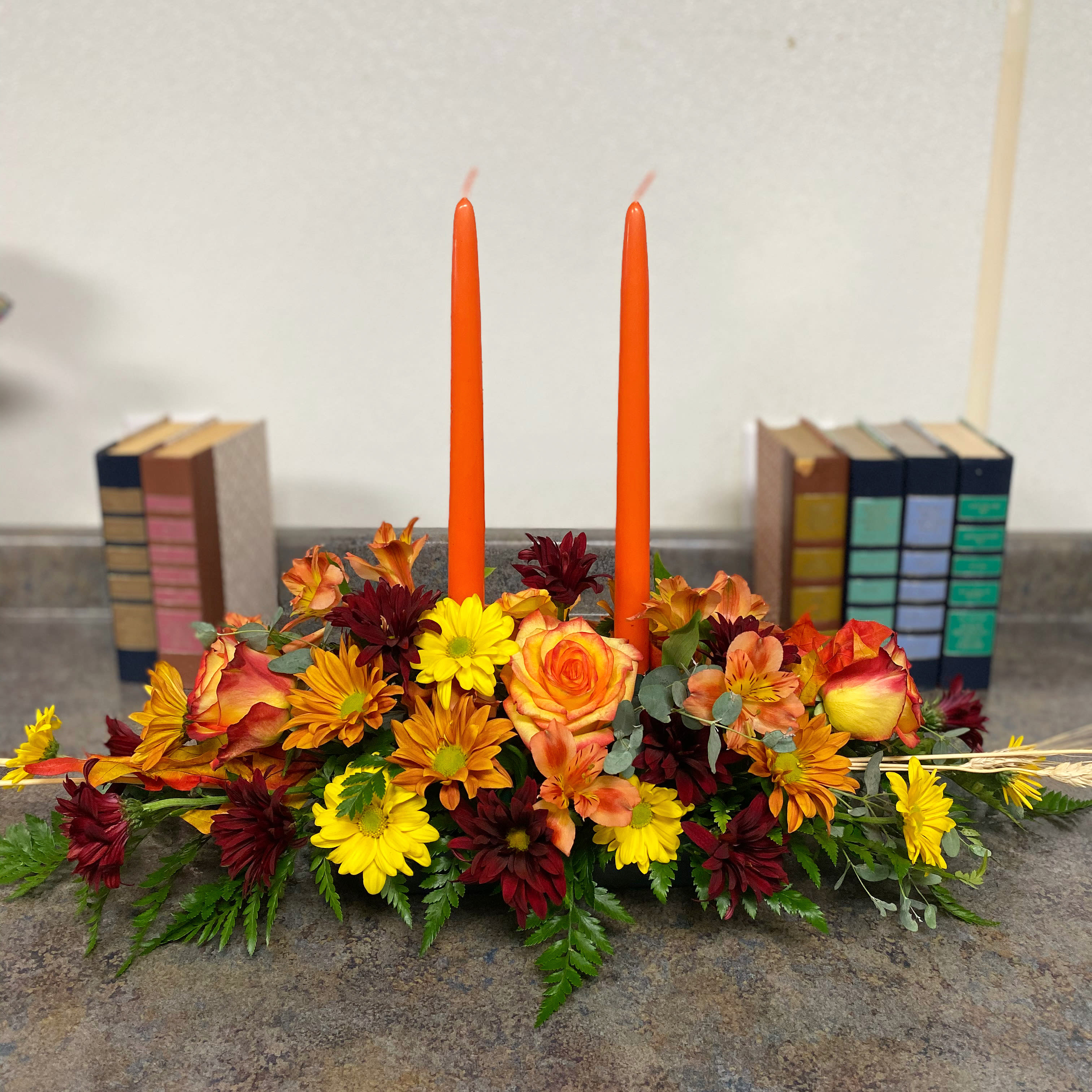 Family Gathering Centerpiece - As your loved ones gather around the table they'll bask in the warm glow of two orange taper candles surrounded by a fantastic array of fall flowers.