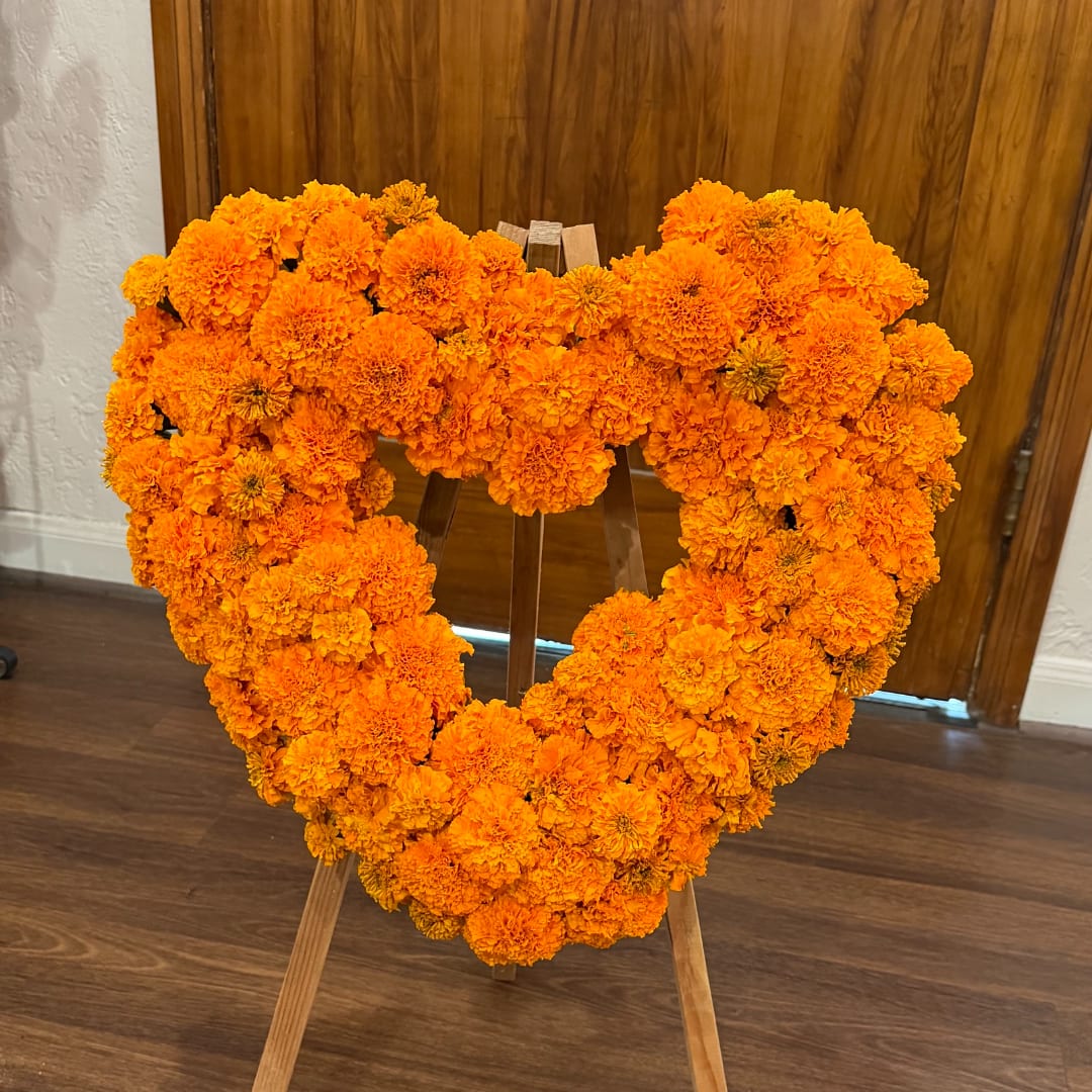 Heart-shaped marigold floral wreath on a wooden stand