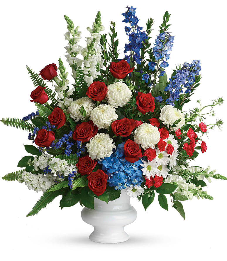 With Distinction Bouquet - A dazzling display of patriotic red, white and blue flowers sends a silent yet poignant statement about hope, freedom and the strength to endure. This proud bouquet is a testament to life that is sure to be appreciated. A beautiful mix of all-American red, white and blue flowers such as hydrangea, roses, miniature carnations, snapdragons, chrysanthemums and more are perfectly arranged in a white urn. Approximately 31" W x 34 1/2" H 