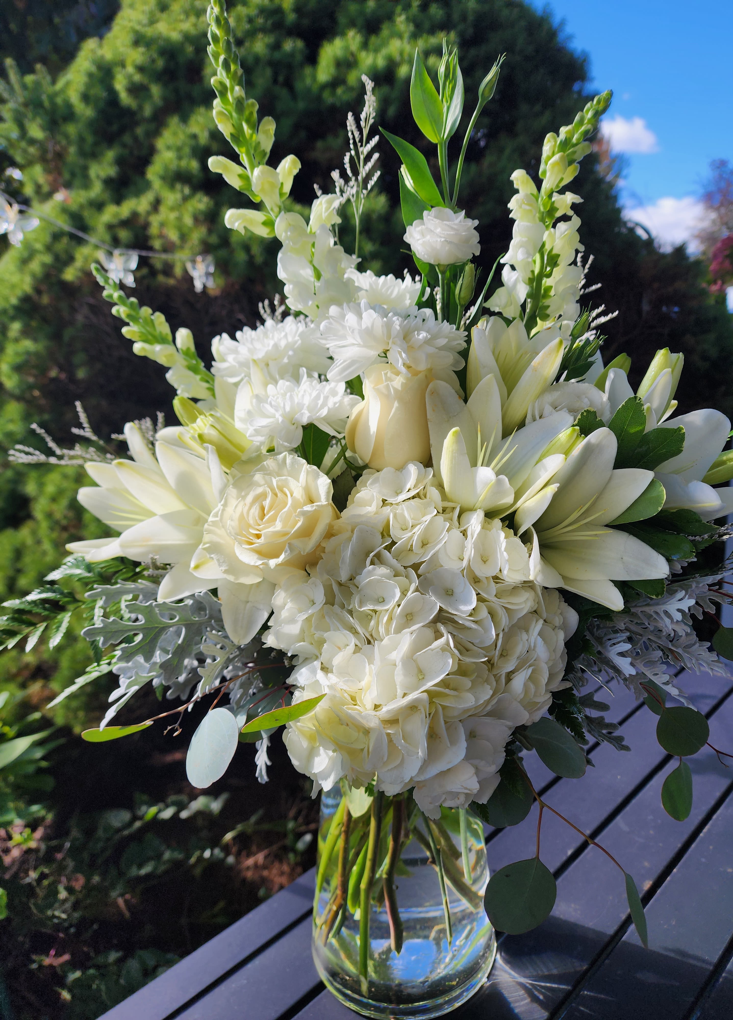 White floral bouquet in a clear glass vase with tall blooms and round greenery