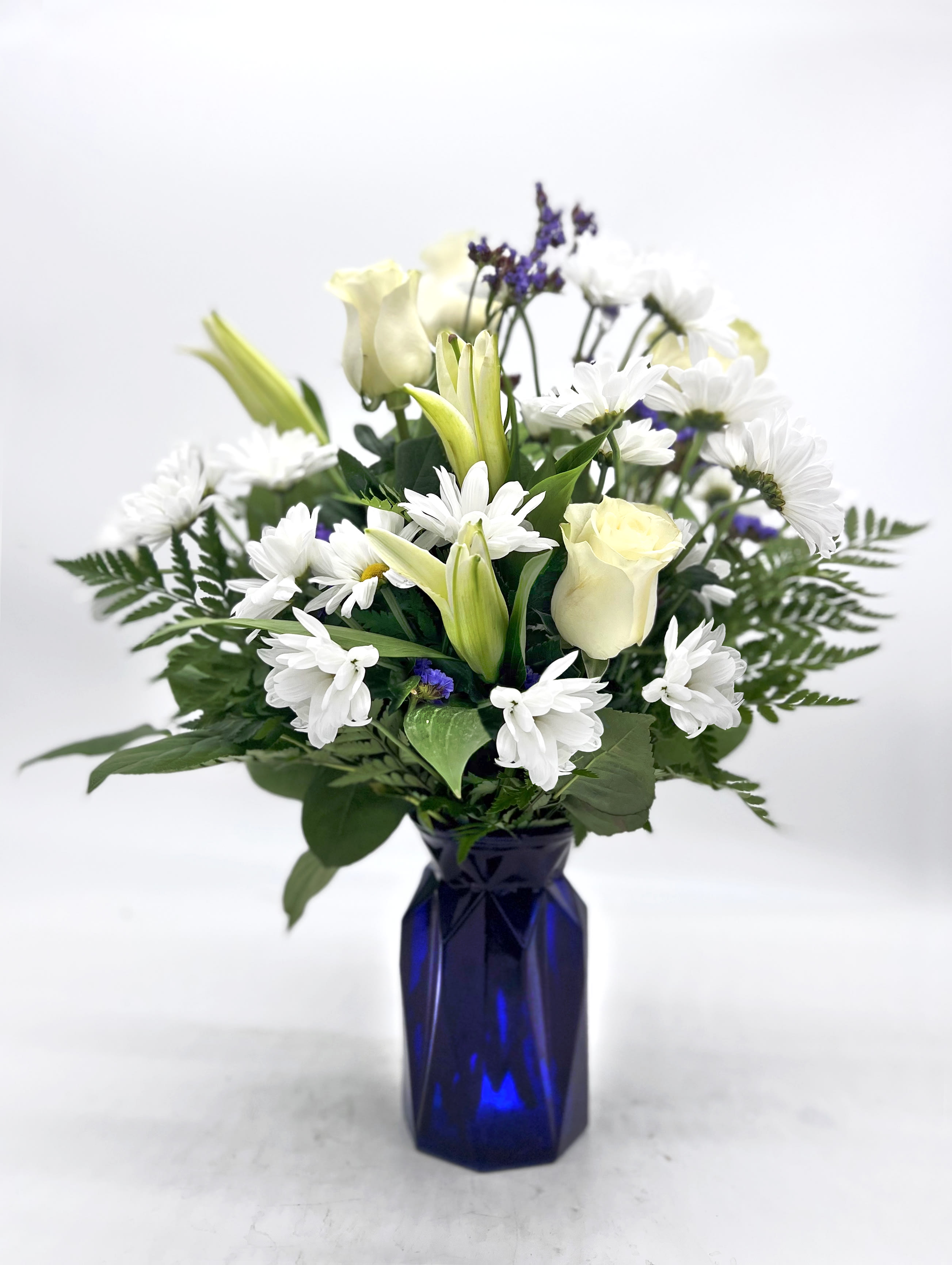 White flowers and pale yellow roses arranged in a blue vase