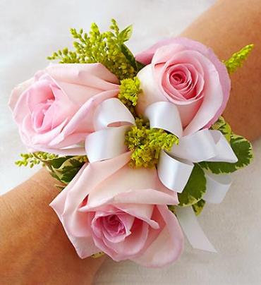 Pink rose wrist corsage with white ribbon and green accents