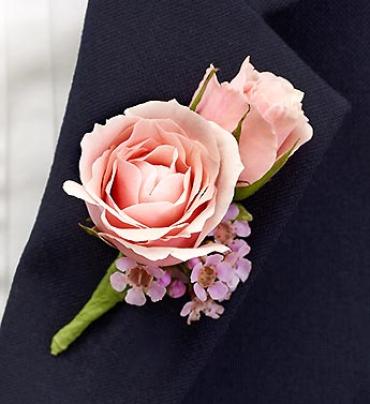 Pink rose boutonniere with small lavender flowers on dark fabric