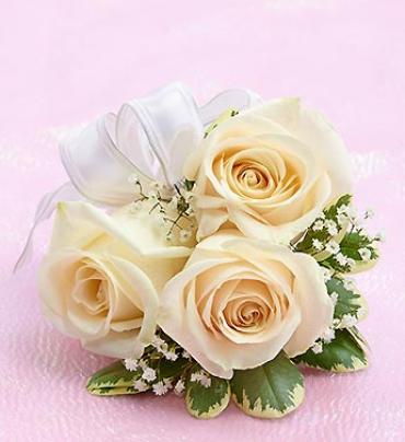 Cream roses with white ribbon and small filler flowers on a pink background