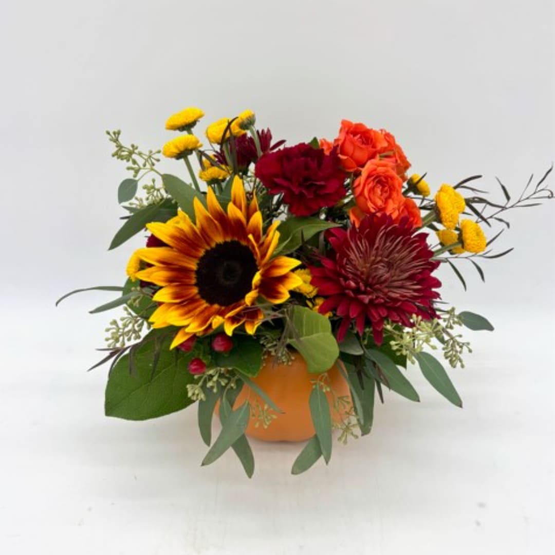 Bouquet with sunflowers, orange roses, and burgundy blooms in an orange vase