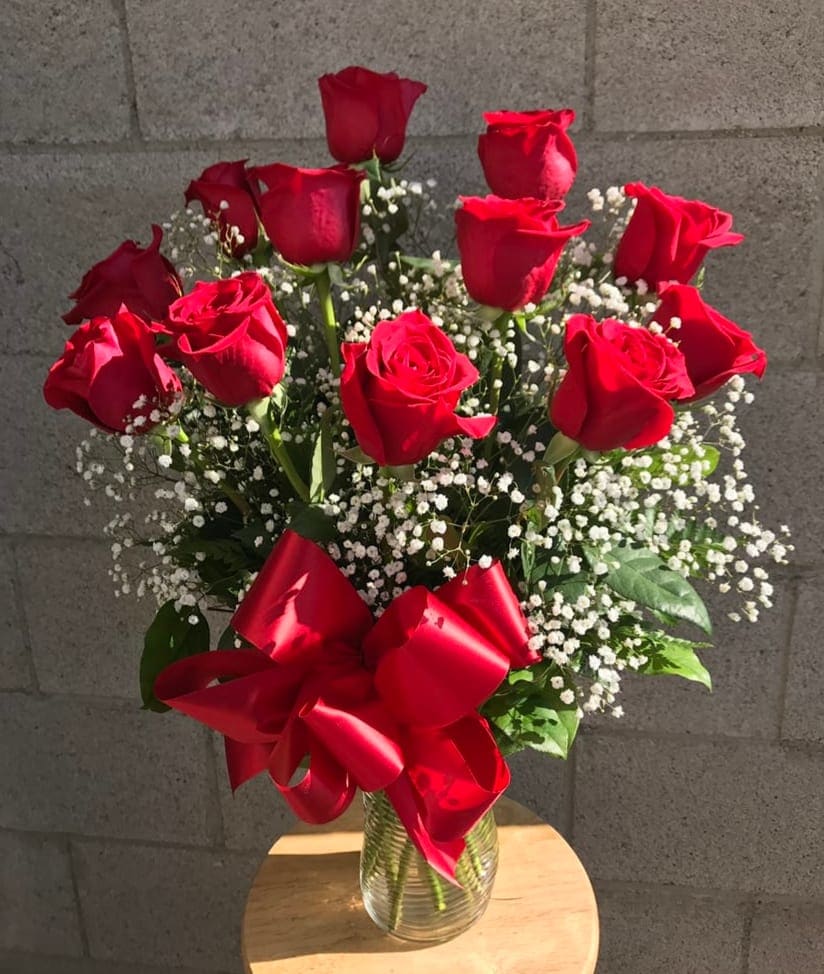 Bouquet of red roses with baby's breath in a glass vase and red ribbon