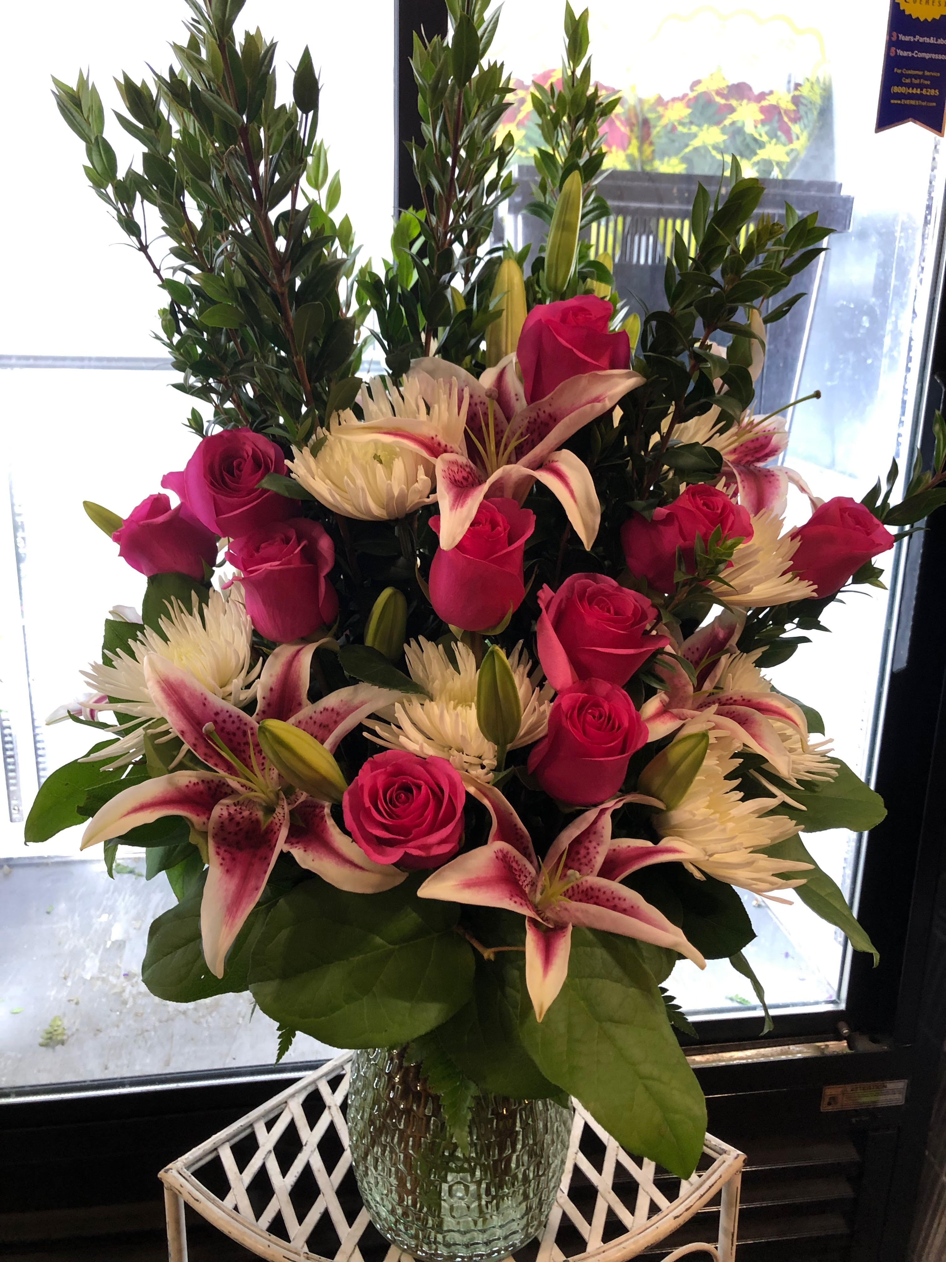 Pink roses and lilies arranged in a clear glass vase