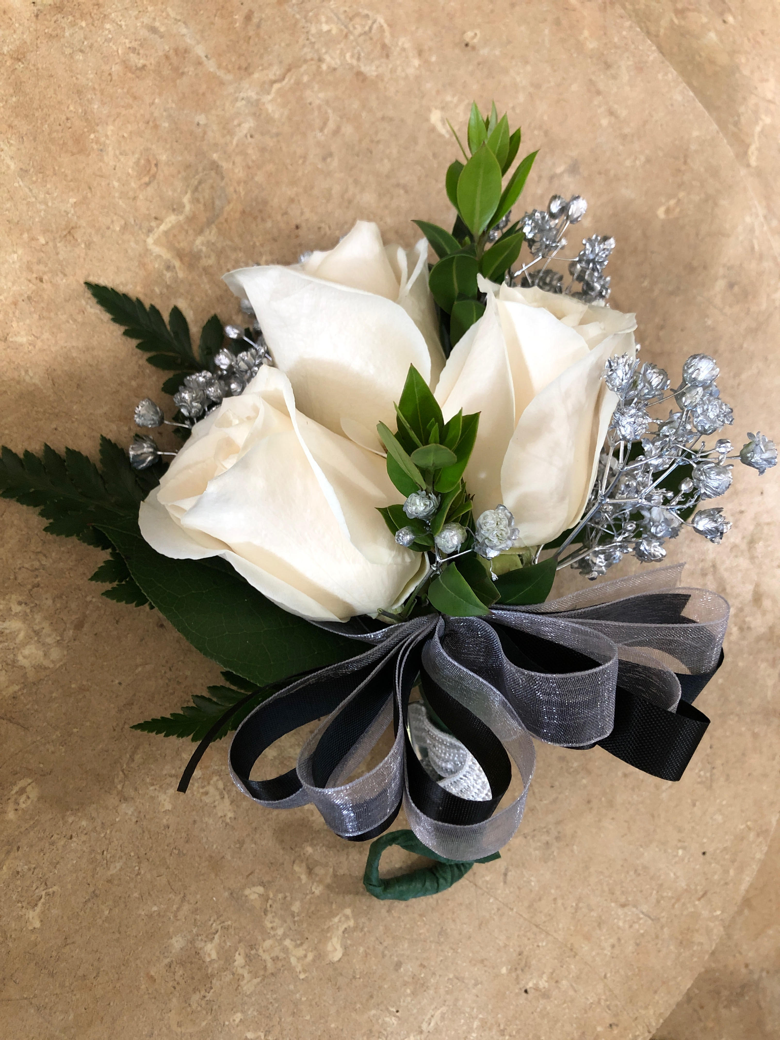 White rose boutonniere with silver filler and a black-gray ribbon