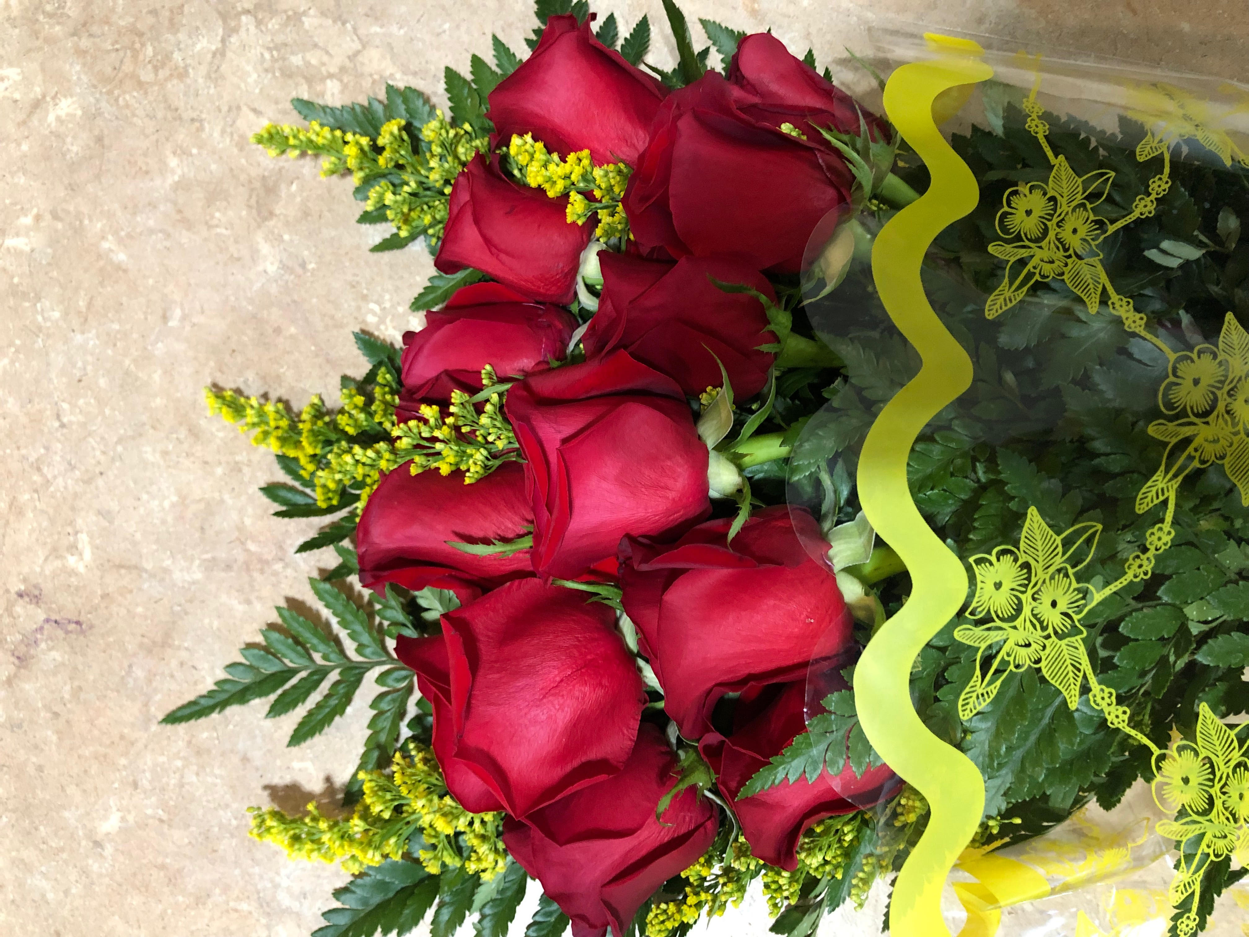 Bouquet of red roses wrapped in clear plastic with yellow ribbon