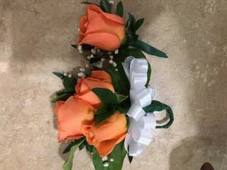 Orange rose corsage with white ribbon on a beige background