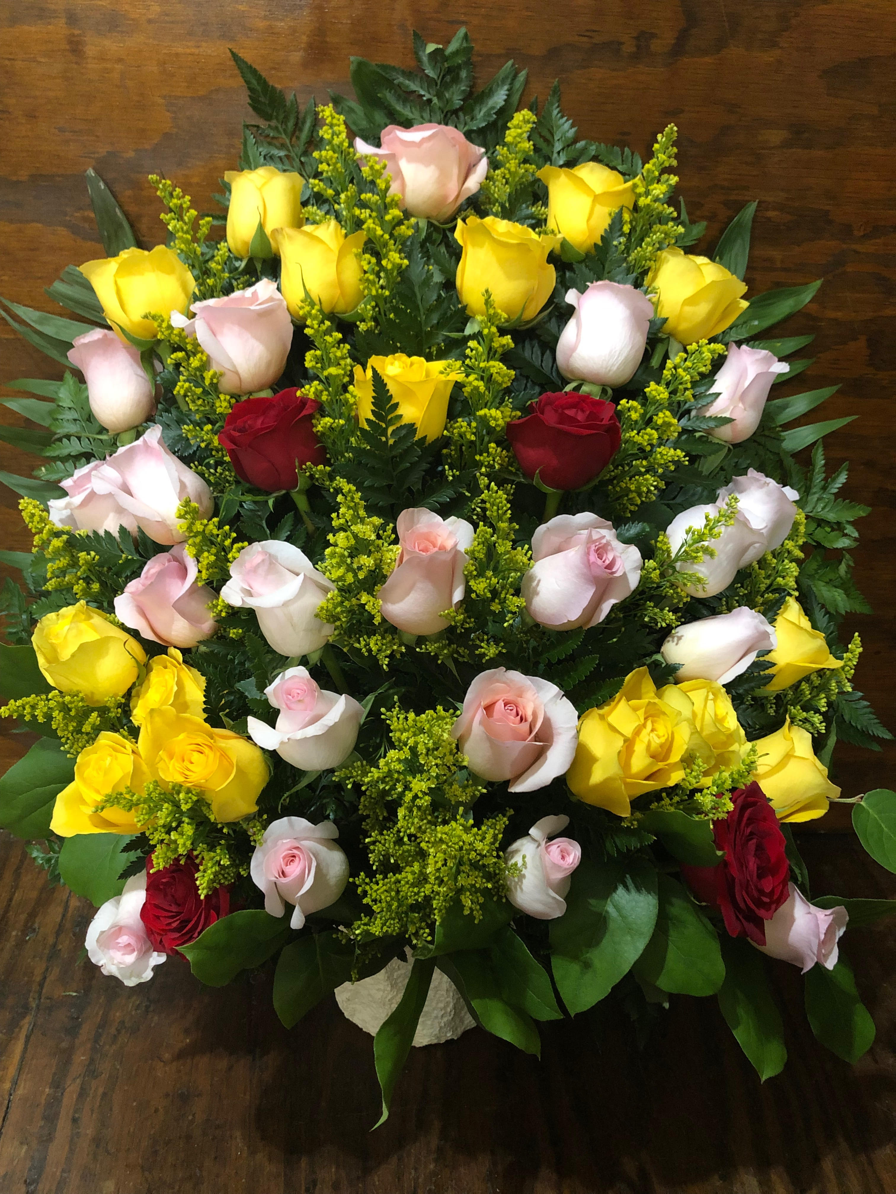 Tiered bouquet of yellow, pink, and red roses with greenery