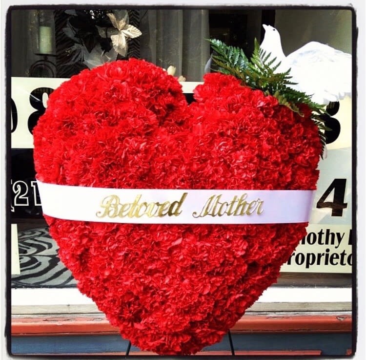 Heart-shaped red carnation arrangement with a white ribbon