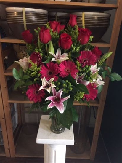 Bouquet of red roses, pink lilies, and magenta gerbera daisies in a glass vase
