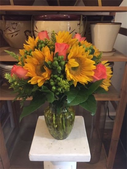 Bouquet of sunflowers and pink roses in a glass vase