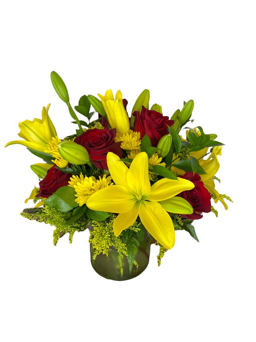 Yellow lilies and red roses arranged in a glass vase