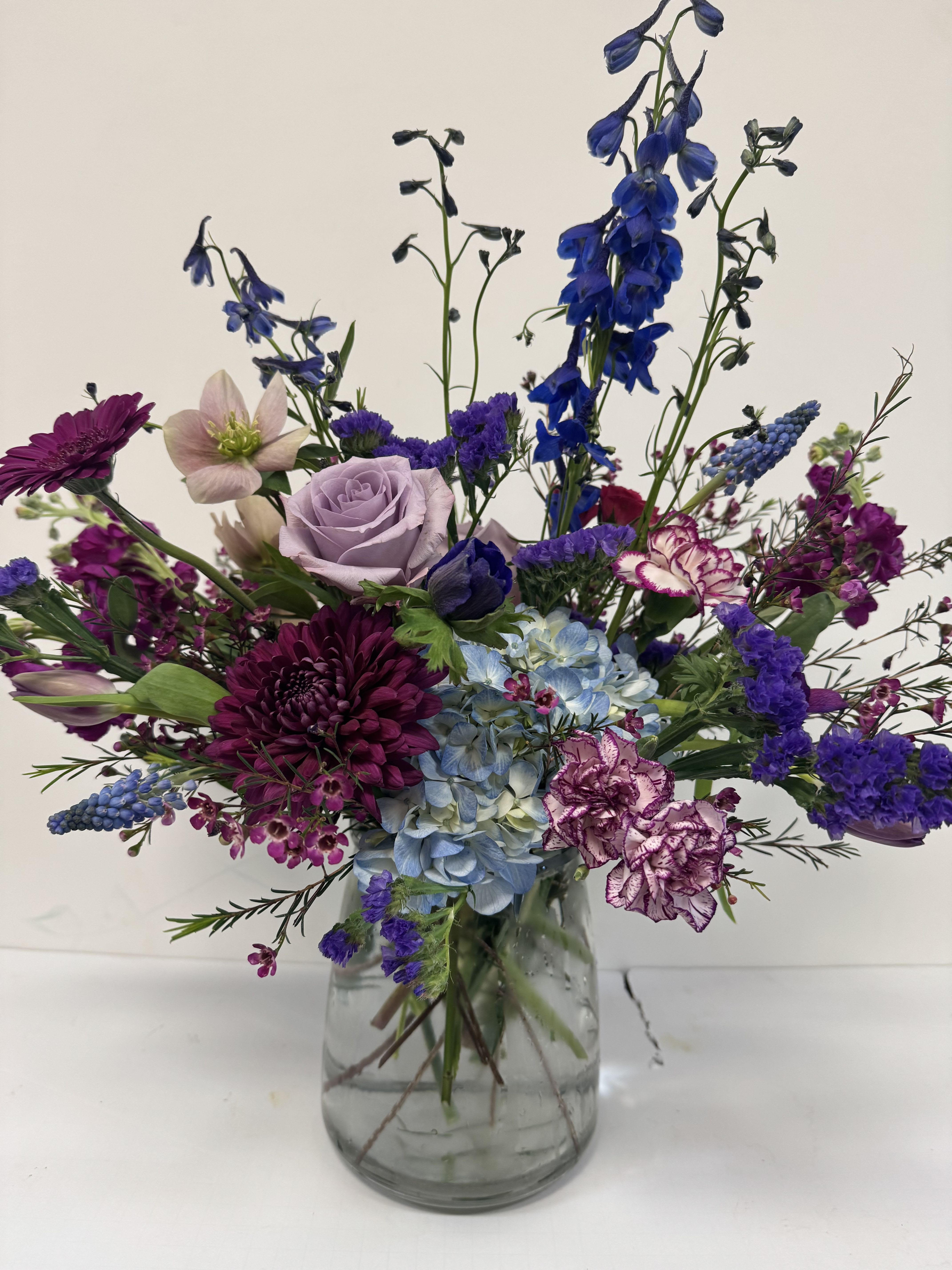 Mixed purple and blue flowers arranged in a clear glass vase